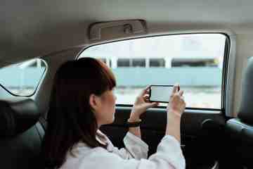 mujer en un auto tomando fotografías de con su celular