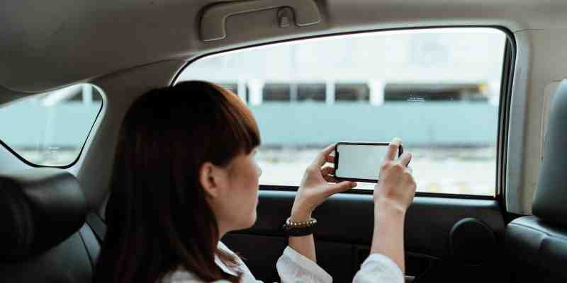 mujer en un auto tomando fotografías de con su celular